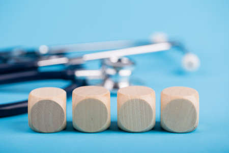 Stethoscope with four wooden blocks on blue background.の写真素材