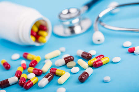 Medicine and stethoscope on blue background.
