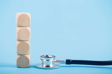 Stethoscope with four wooden blocks on blue background.の写真素材