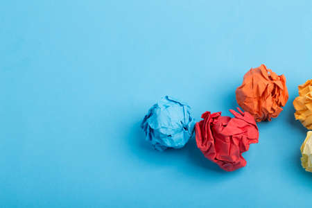 Crumpled paper ball up piece of paper on blue background.