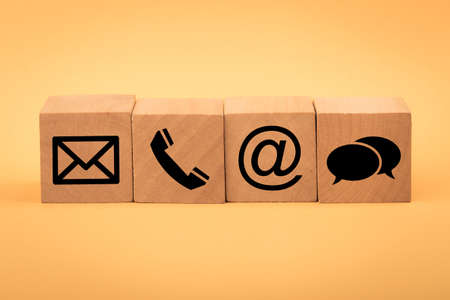 Contact Methods. Close-up of a phone, email, chat and post icons wooden block.の写真素材