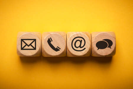 Contact Methods. Close-up of a phone, email, chat and post icons wooden block.の写真素材