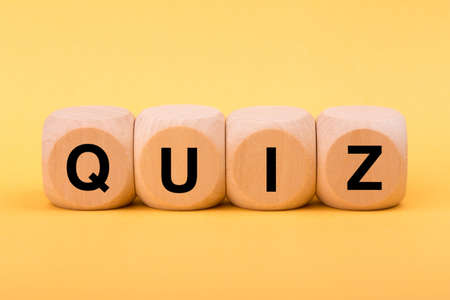 Quiz concept wooden blocks isolated on yellow background.の写真素材