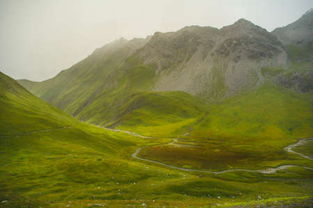 High light in the german alps with green hills and a cloudy mountain top