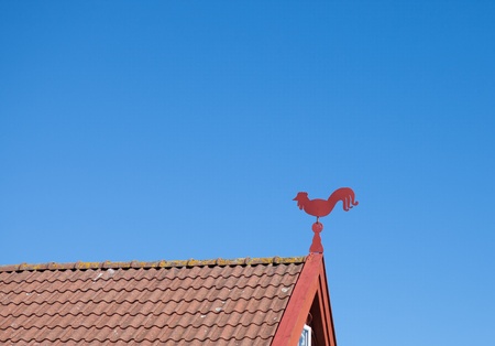 Small weathervane in the shape of a rooster on an old swedish house.の写真素材