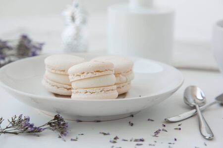 Macarons, morning coffee on light table with blurred vase and blue flowers on backgroundの写真素材