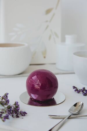 Violet chocolate ball delicious dessert on light white background with flowersの写真素材