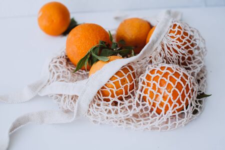 Mesh shopping beg with oranges and phone - nature friendly style. Environmental Conservation Recycling Conceptの写真素材