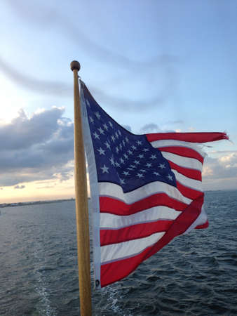 American Flag waving in a breeze above the ocean. の素材