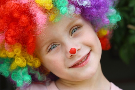 a cute little child dressed up in a clown costume and face paint and smilingの写真素材