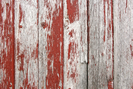 A background of rustic, aged barnwood boards, with peeling red paint の写真素材