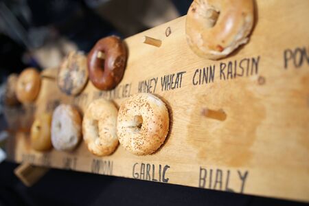 Different flavors and varieties of fresh baked bagels are displayed for sale at a farmer's market.