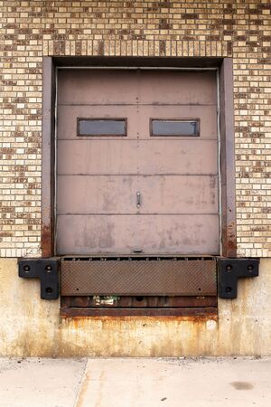 Close up on a rusty old metal truck loading dock door, surrounded by brown brick on an old...