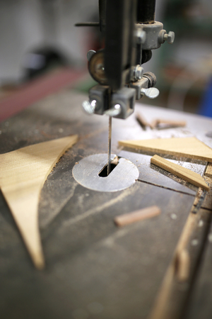A close up on the toothed blade of a band saw, in a home workshop, surrounded by wood scraps and sawdust.の写真素材