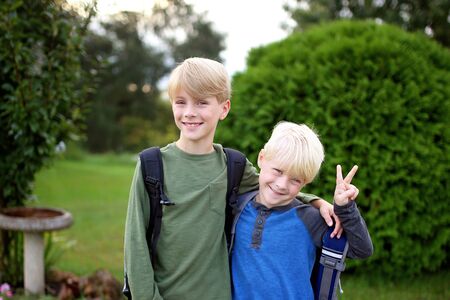 Two young kids are smiling as they have their backpacks and prepare for the first day of school.の写真素材