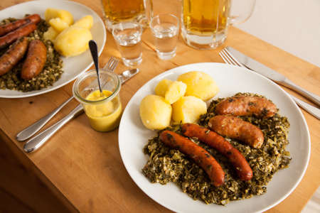 Two dishes of traditional German cabbage with sausage mix, potatoes, mustard, beer and schnappsの写真素材