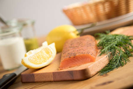 Smoked and stained samlon with lemon and dill on wooden board with horseradish and honey mustard dill sauceの写真素材