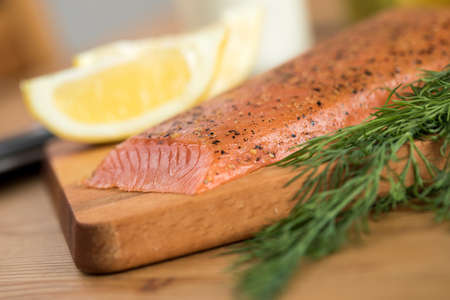 Smoked and stained samlon with lemon and dill on wooden boardの写真素材