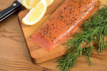 Smoked and stained samlon with lemon and dill on wooden boardの写真素材