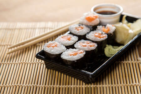 Salmon maki sushi with pickled ginger, soy sauce, wasabi and wooden chopsticksの写真素材