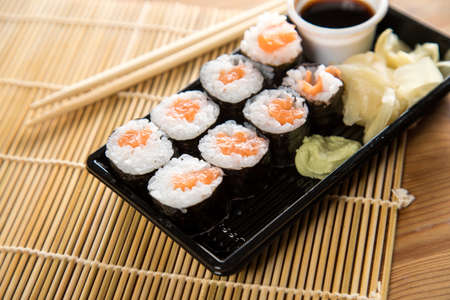 Salmon maki sushi with pickled ginger, soy sauce, wasabi and wooden chopsticksの写真素材