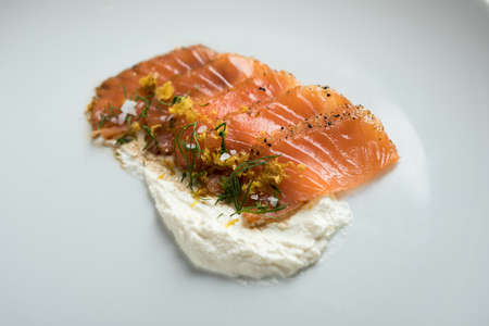 Smoked salmon sashimi slices with horseradish creme fraiche sauce, dill, lemon zest as an appetizer or amuse gueule in gourmet restaurantの写真素材
