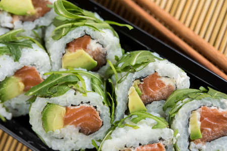 Salmon avocado rocks inside out with chopsticks in take away trayの写真素材