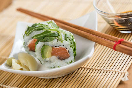 Salmon avocado rocks out of sushi with soy sauce, wasabi, pickled ginger and chopsticksの写真素材