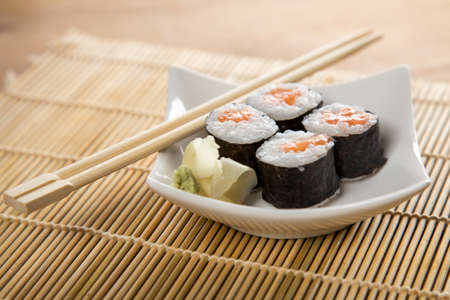 Salmon maki sushi rolls with wasabi, pickled ginger and wooden chopsticksの写真素材