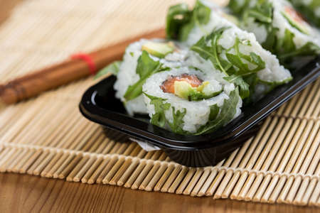 Salmon avocado rocks inside out with chopsticks in take away trayの写真素材