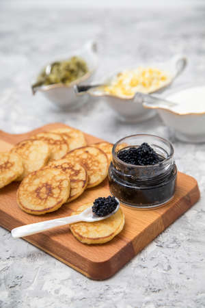 Black caviar on pearl spoon with blinis, sour cream, cucumber relish and chopped eggの写真素材
