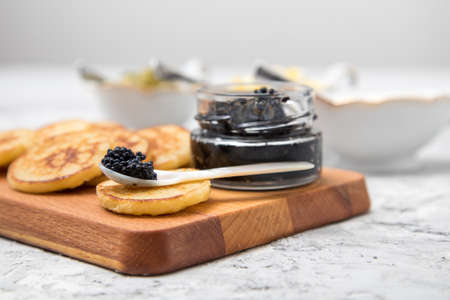 Black caviar on pearl spoon with blinis, sour cream, cucumber relish and chopped eggの写真素材