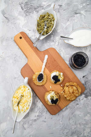 Black caviar on pearl spoon with blinis, sour cream, cucumber relish and chopped eggの写真素材