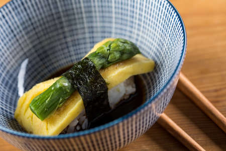 Japanese Tamago omelette nigiri with green asparagus and soy sauce in bowlの写真素材