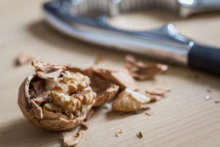 Cracked walnut nutshell and nutcracker on wooden domestic kitchen countertopの写真素材