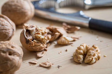 Cracked walnut nutshell and nutcracker on wooden domestic kitchen countertopの写真素材