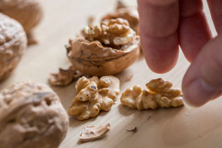Woman eating cracked walnut of wooden domestic kitchen countertopの写真素材