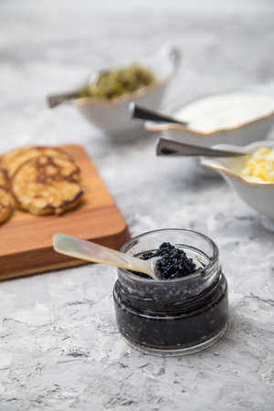 Black caviar on pearl spoon with blinis, sour cream, cucumber relish and chopped eggの写真素材