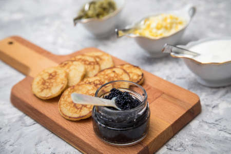 Black caviar on pearl spoon with blinis, sour cream, cucumber relish and chopped eggの写真素材