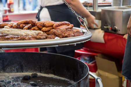 Swing BBQ barbeque barbecue food stall with pork neck steaks, German Bratwurst and Krakauer sausages during city festival fairの写真素材