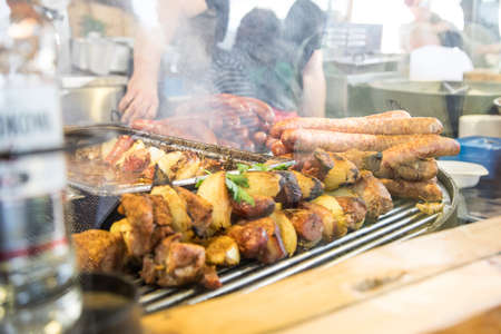 Meat skewer and Krakow sausages at barbeque BBQ grill barn during German folk festivalの写真素材