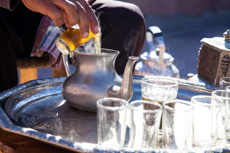 Man at preparation of Moroccan mint tea ceremony with glass and teapot in Marrakech Moroccoの写真素材