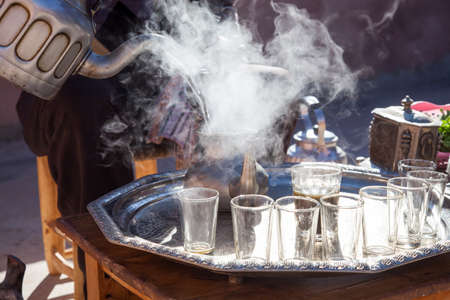 Man at preparation of Moroccan mint tea ceremony with glass and teapot in Marrakech Moroccoの写真素材