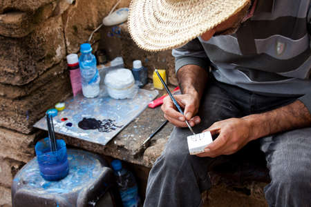 Moroccan artist painter with brush, canvas und color outside on the go in Marrakech Moroccoの写真素材