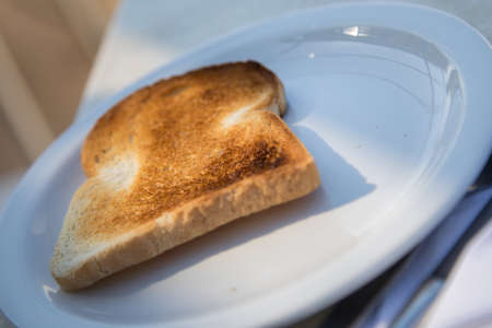 Slice of roasted breakfast toast in sunlight of hotel cafe terraceの写真素材