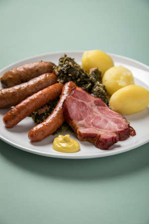 Oldenburger green cabbage with sausage mix, Kassler pork neck, boiled potatoes and mustard is an traditional German winter dishの写真素材