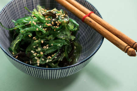 Japanese Wakame seaweed salad with sesame seeds with chopsticks in bowlの写真素材