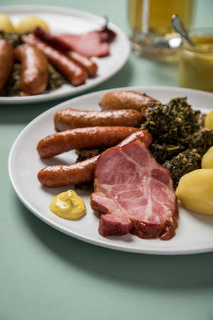 Oldenburger green cabbage with sausage mix, Kassler pork neck, boiled potatoes and mustard is an traditional German winter dishの写真素材