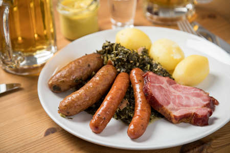 Oldenburger green cabbage with sausage mix, Kassler pork neck, boiled potatoes, mustard, beer and grain liquor is an traditional German winter dishの写真素材
