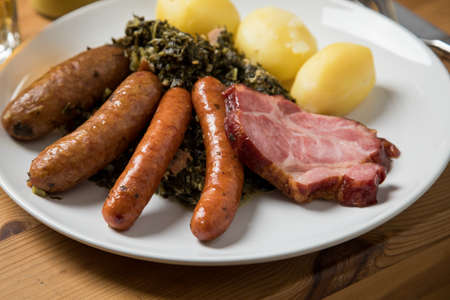 Oldenburger green cabbage with sausage mix, Kassler pork neck and boiled potatoes is an traditional German winter dishの写真素材